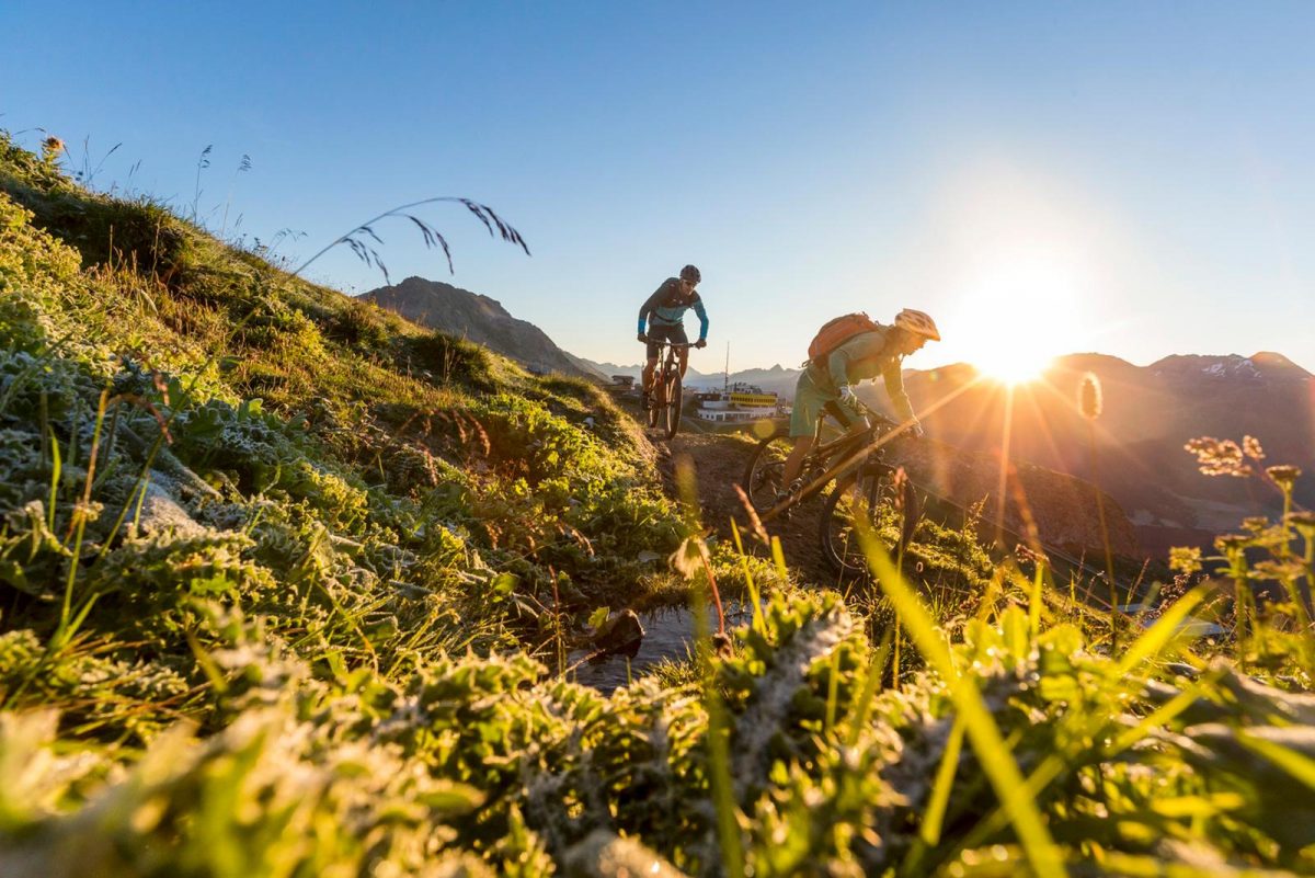 Two mountain bikers go down a mountain trail in the Engadin, Switzerland