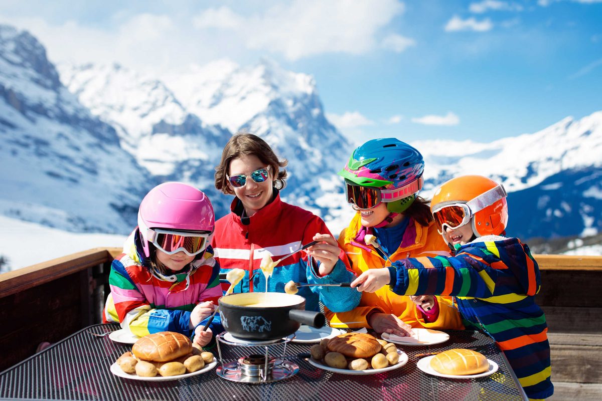 A family eating an après-ski lunch of cheese fondue and raclette