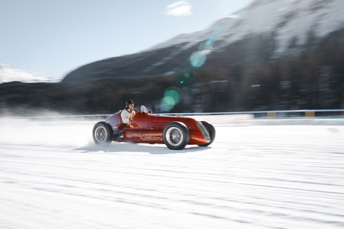 Red classic car racing on snow at The ICE, St. Moritz