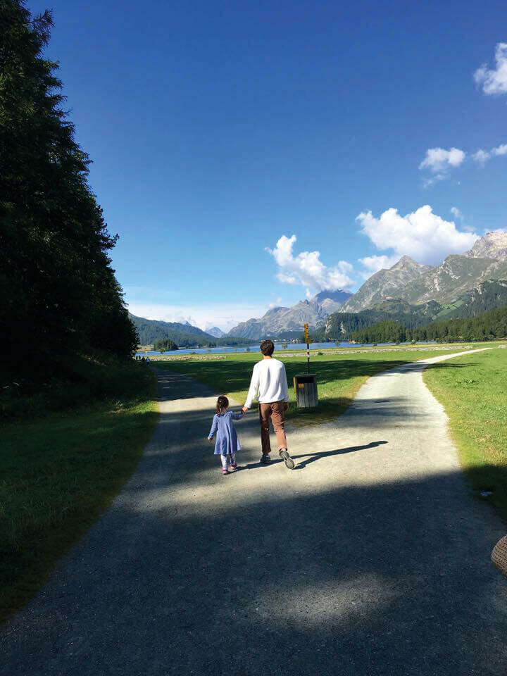 Father and daughter walking towards a mountain lake