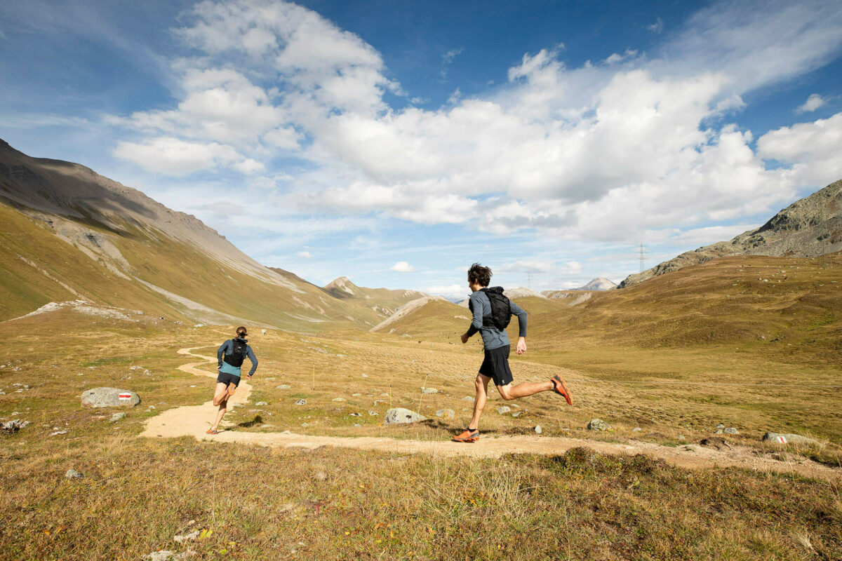 A couple running through a mountain valley