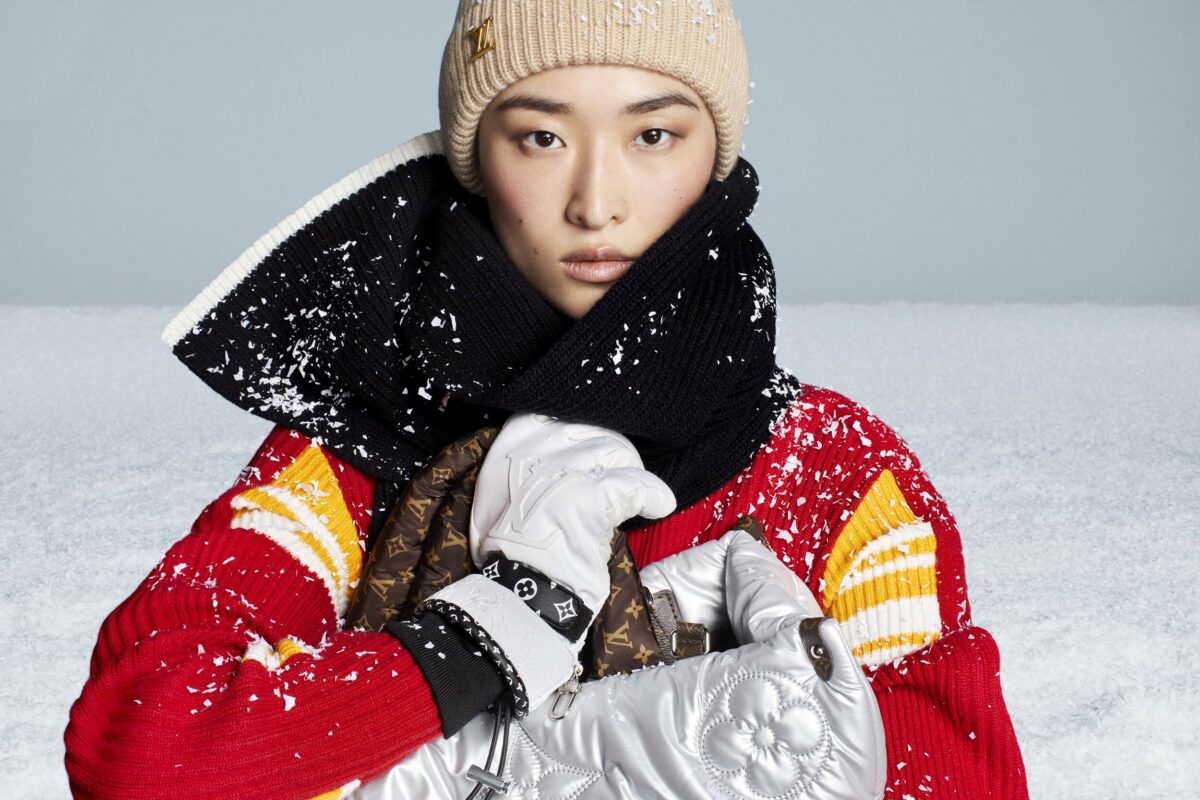 Model in warm designer clothes with snowy backdrop