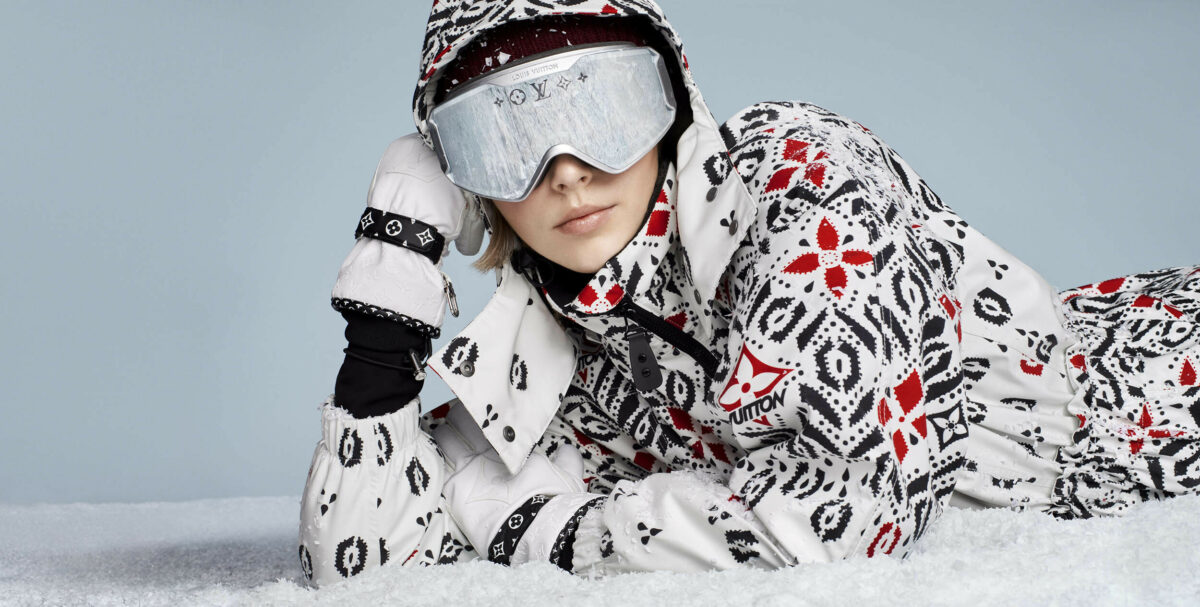 Model wearing ski goggles and patterned ski suit