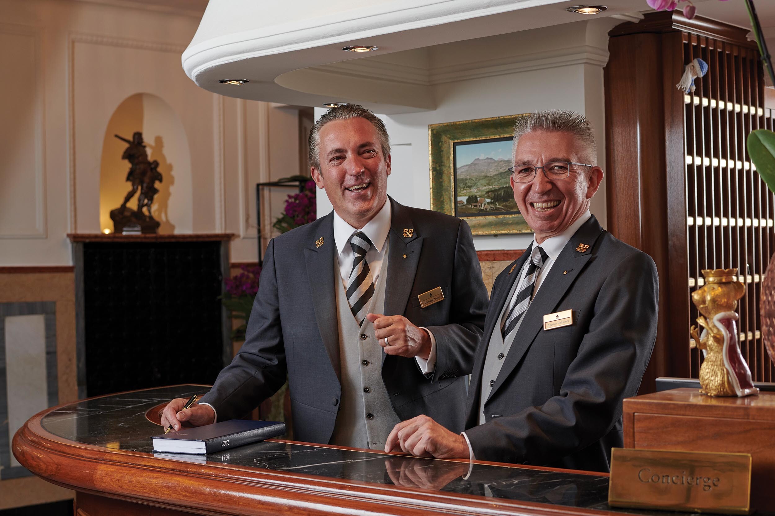 Two hotel concierges smiling at the desk