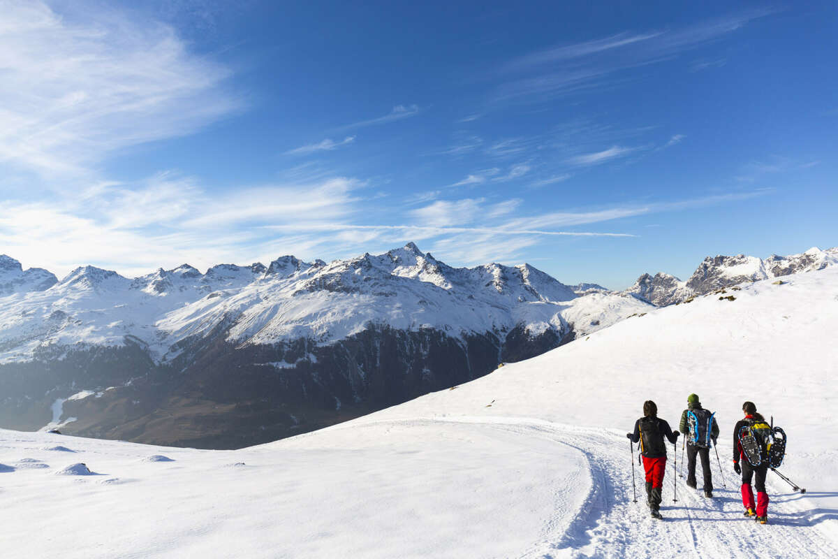 Three winter walkers on a mountain trail 