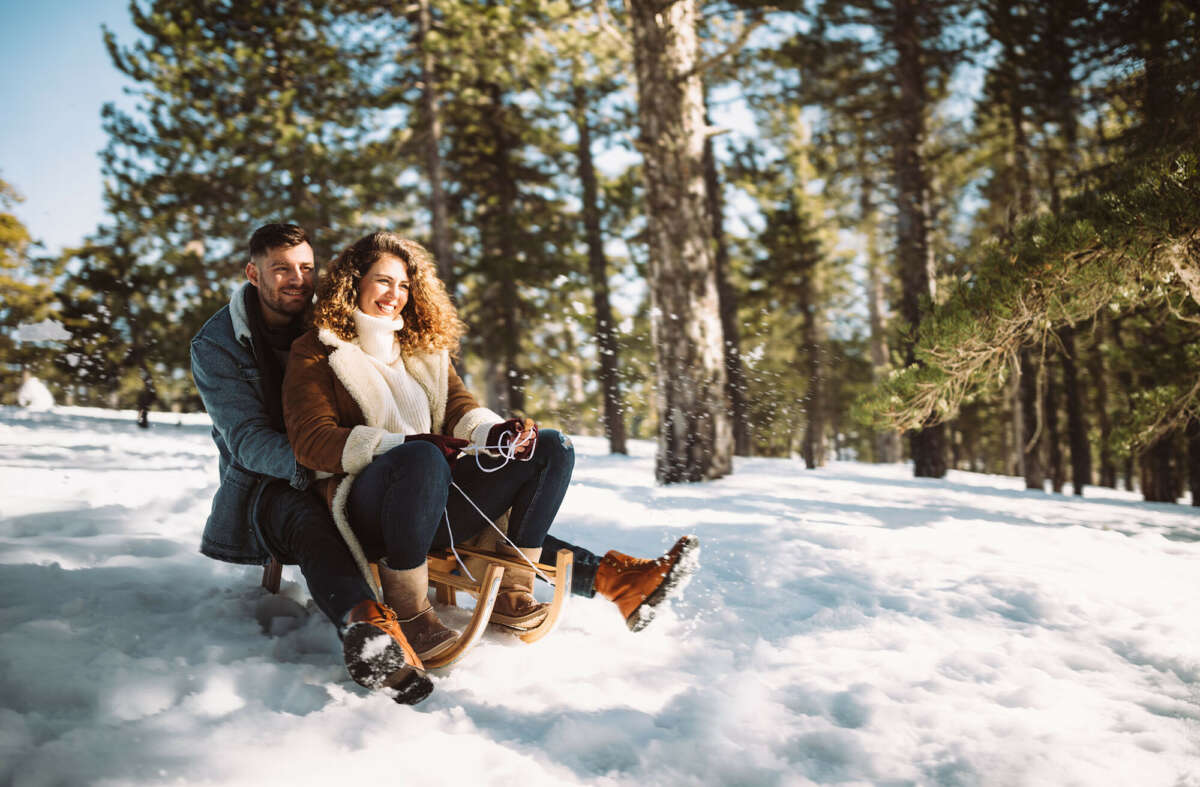 Couple smiling on sledge in snowy forest