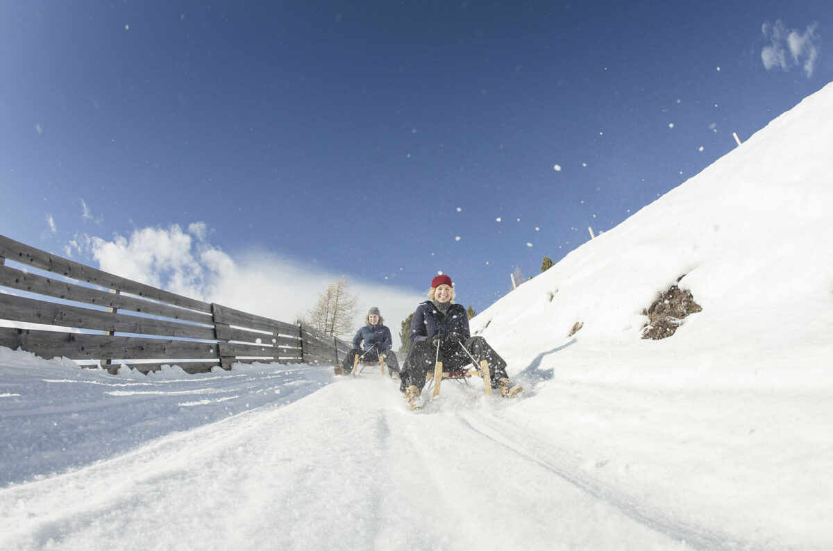 Freunde schlitteln einen Berg hinunter