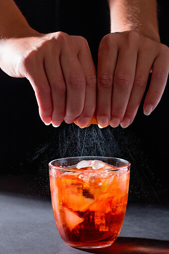 Ein Barkeeper gibt einem Orangen-Mocktail den letzten Schliff