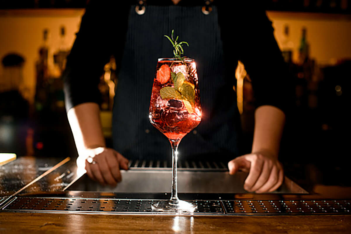 A red mocktail garnished with fruit and herbs 