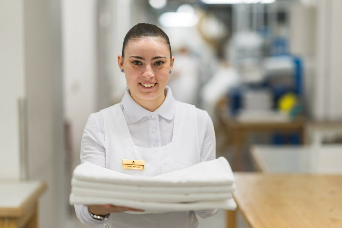 A hotel staff member holding folded laundry