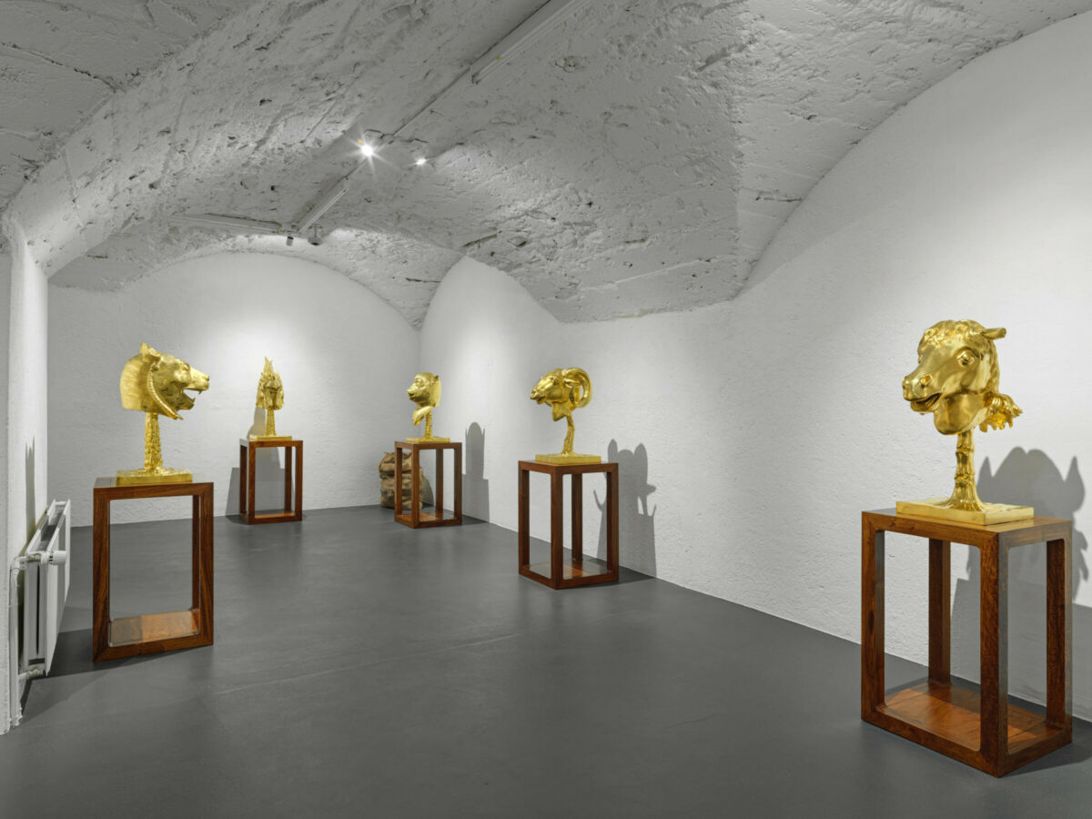 Gold sculptures of animal heads in an exhibition space