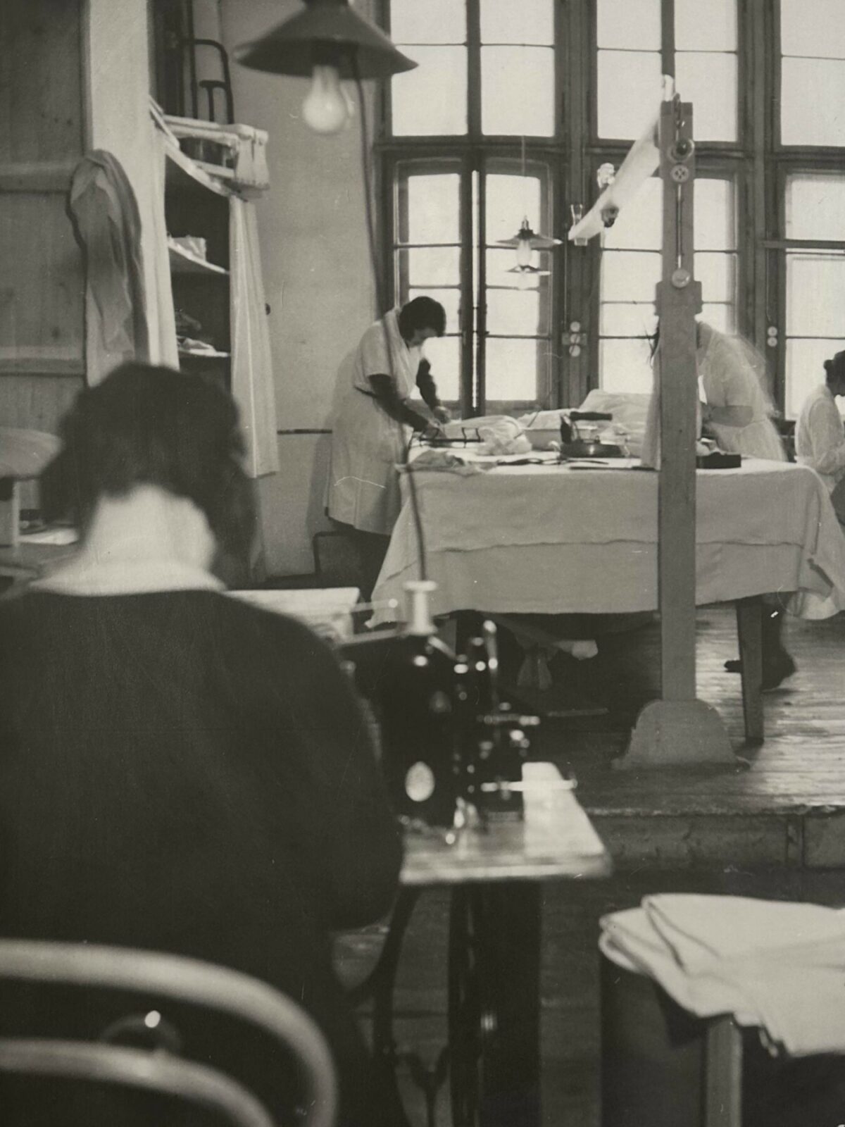 Black and white photo of hotel housekeeping department sewing and ironing