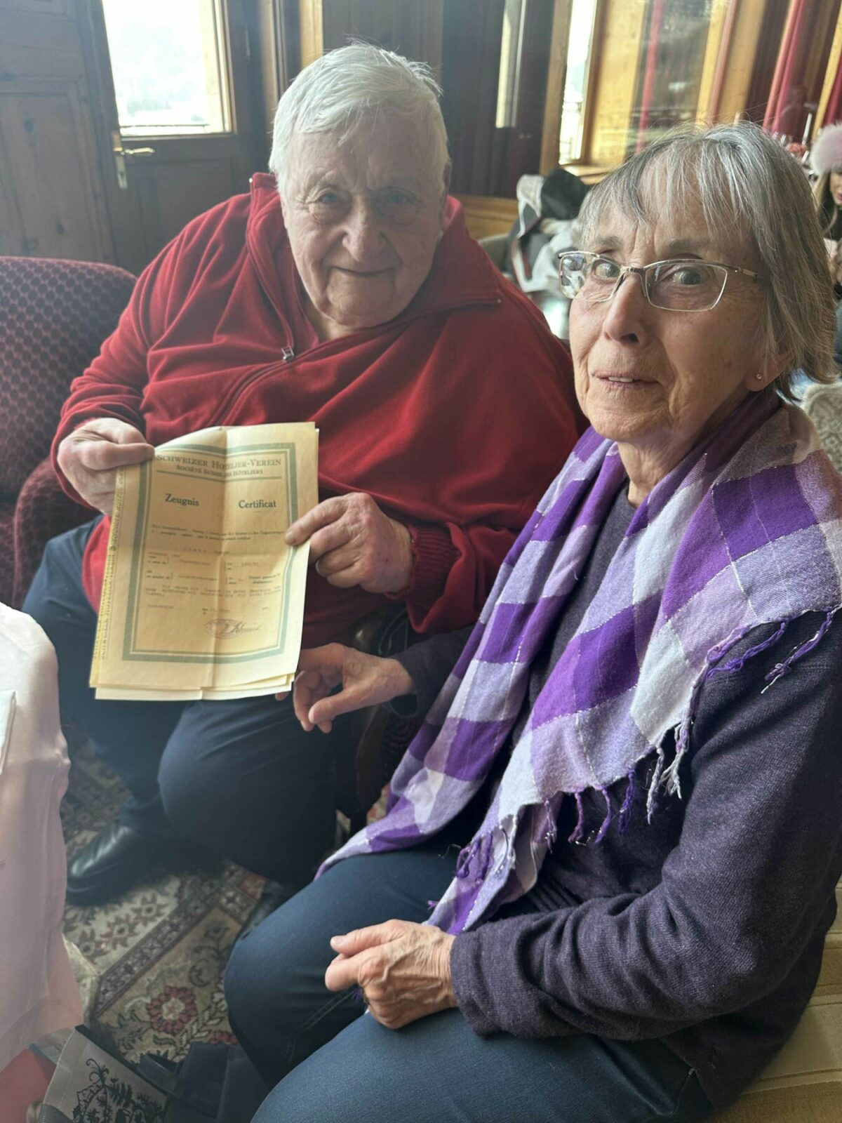 A man with female companion holds up documents belonging to his mother