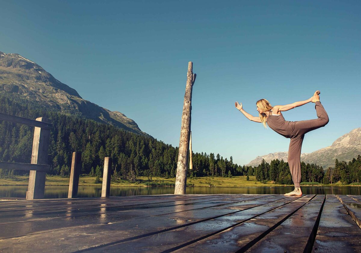 Woman practising yoga on edge of lake