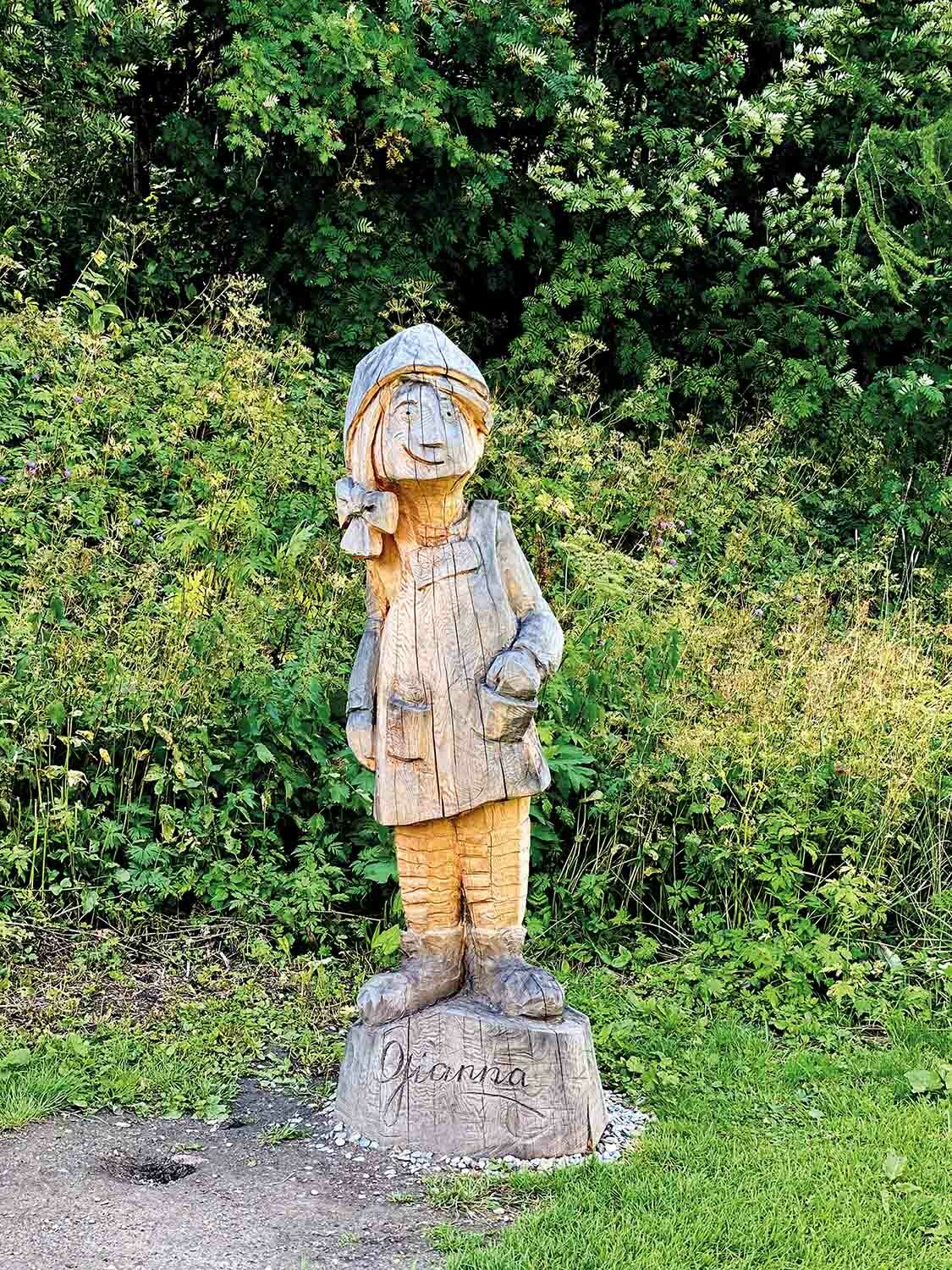 Holzskulptur eines Mädchens im Freien