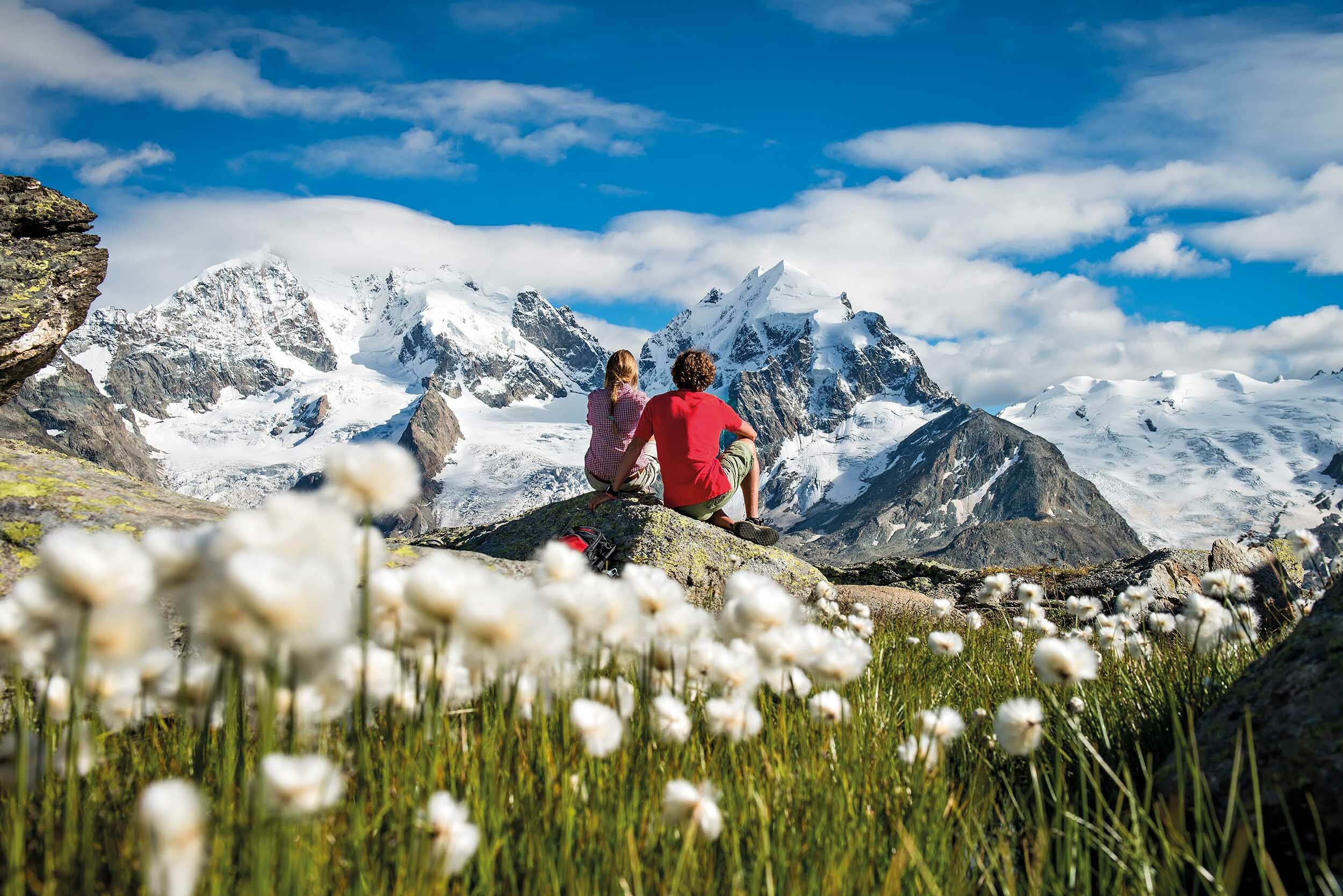 Couple of walkers admire the view of snow-peaked mountains