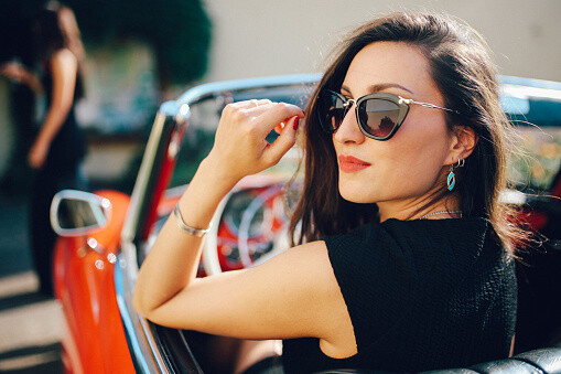 Anspruchsvolle Frau mit Sonnenbrille im Cabrio