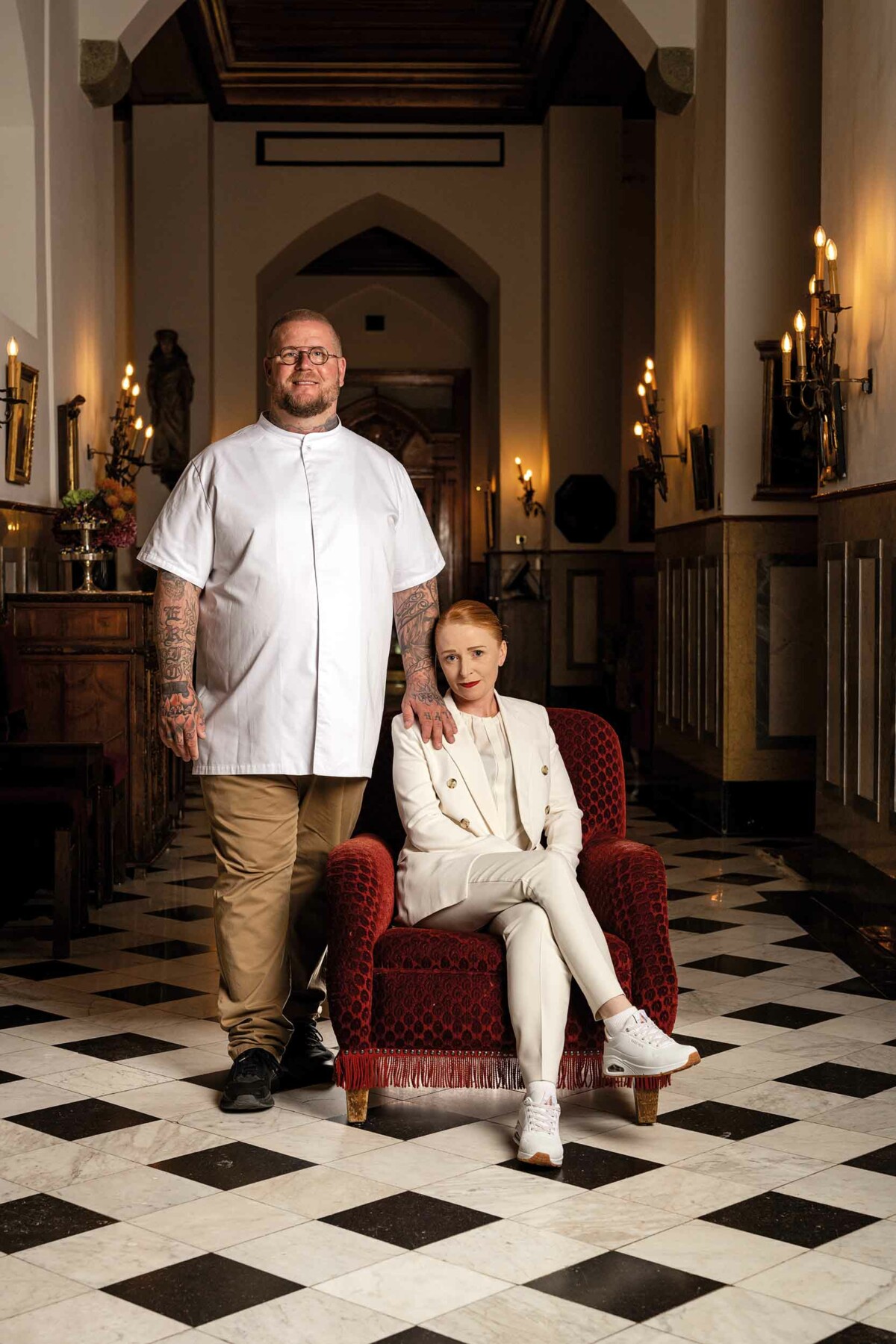 Chef standing next to restaurant manager in velvet chair