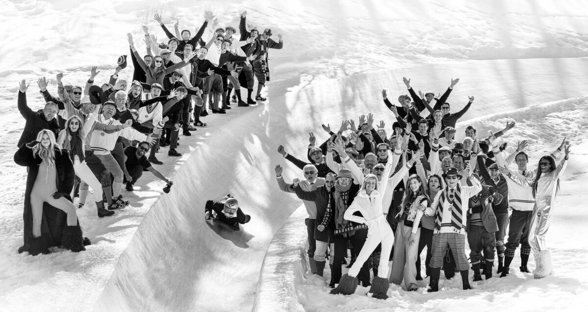 Person on toboggan run surrounded by people waving