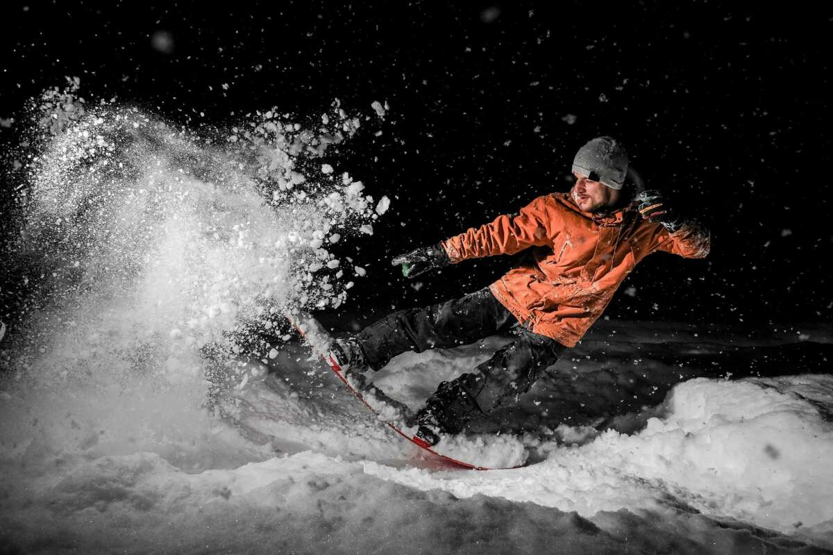 Freeride snowboarder on powder snow at night