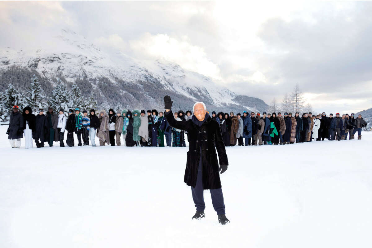 Man waving in snowy landscape with people in the background